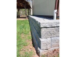 Stone retaining wall installed beside a home with fresh lawn area