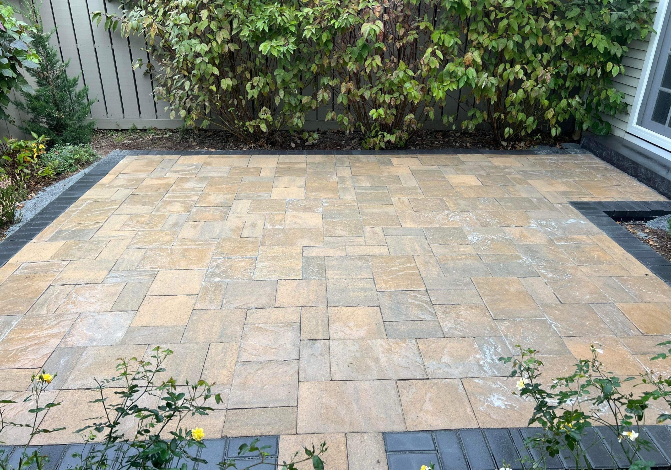 Paver patio area with mixed-color stone pavers beside a privacy fence